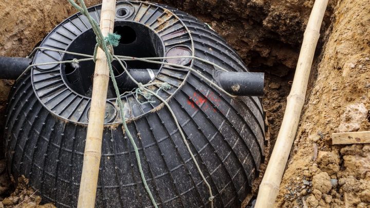Septic tank being lowered into an excavated pit in bare soil