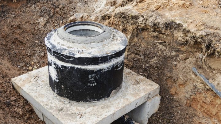 Concrete well rings with cast iron hatch and tools at the excavation