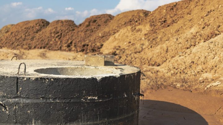 Open concrete ring septic well filled with dark wastewater
