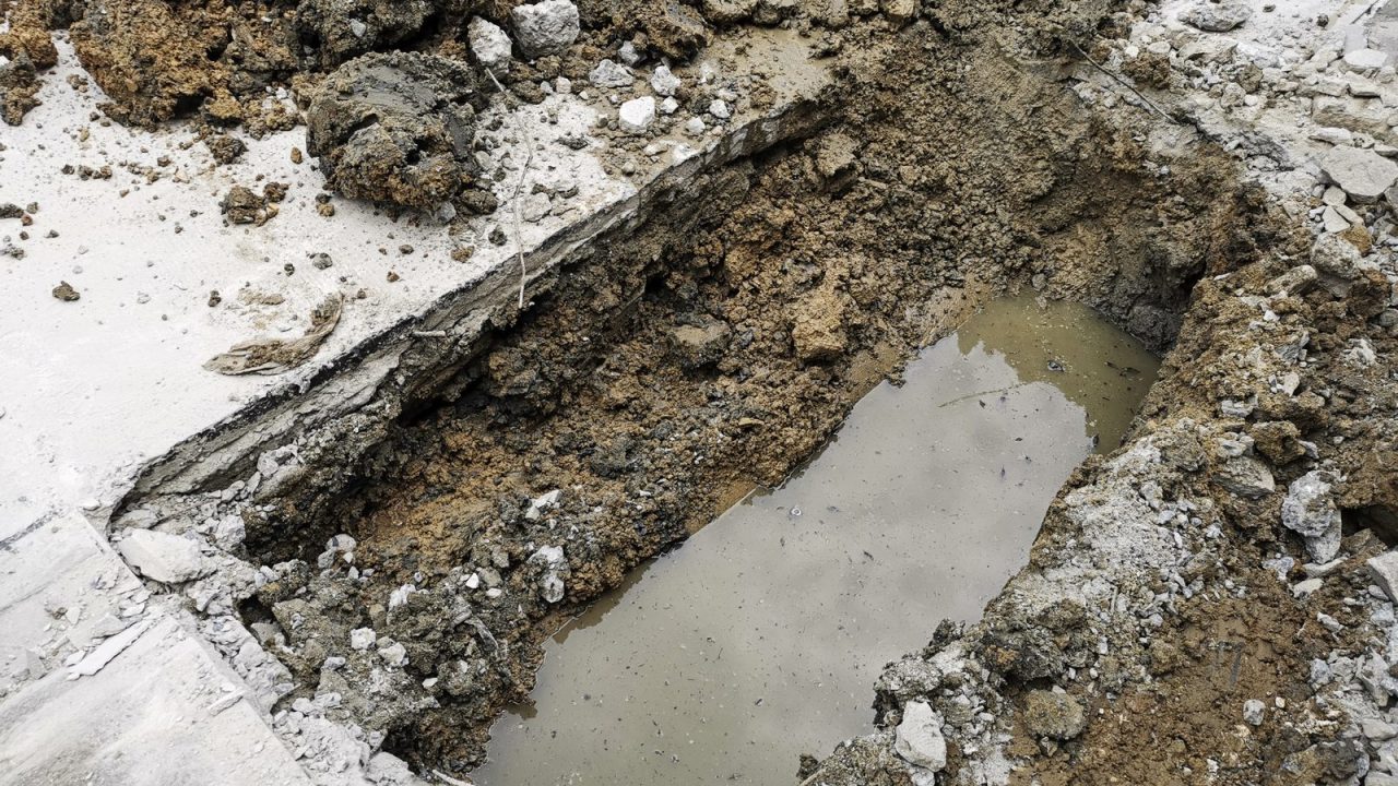 Street dug open with water pipe sections laid in the excavation