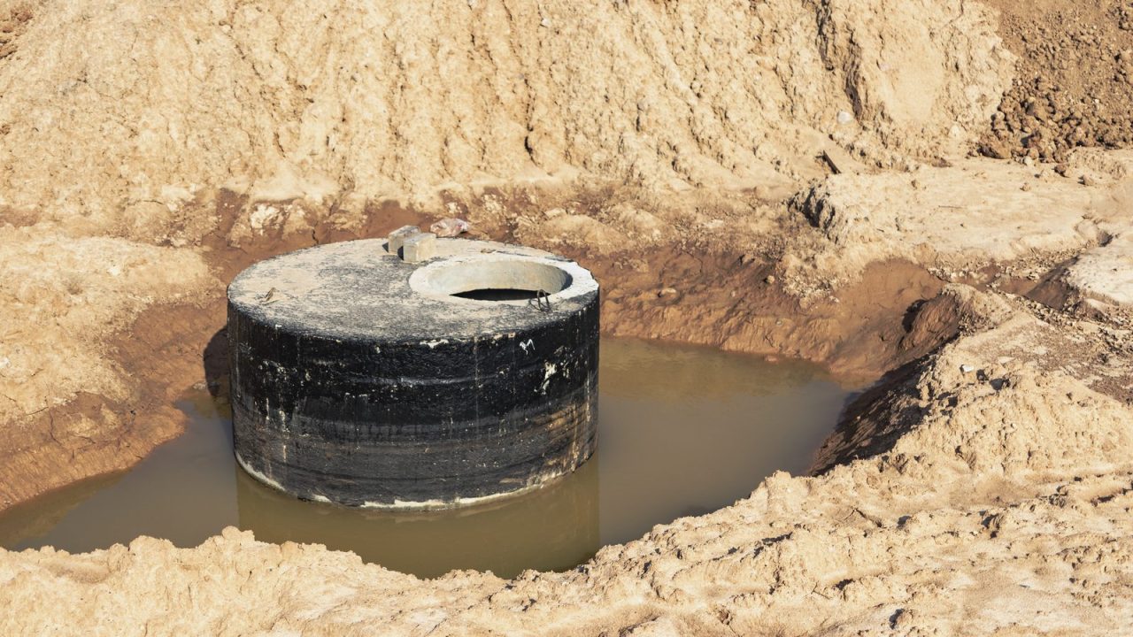Concrete ring sewer well holding wastewater, rings exposed at grade