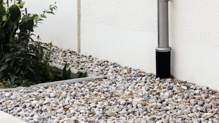French drain pipe bedded in gravel alongside a house foundation