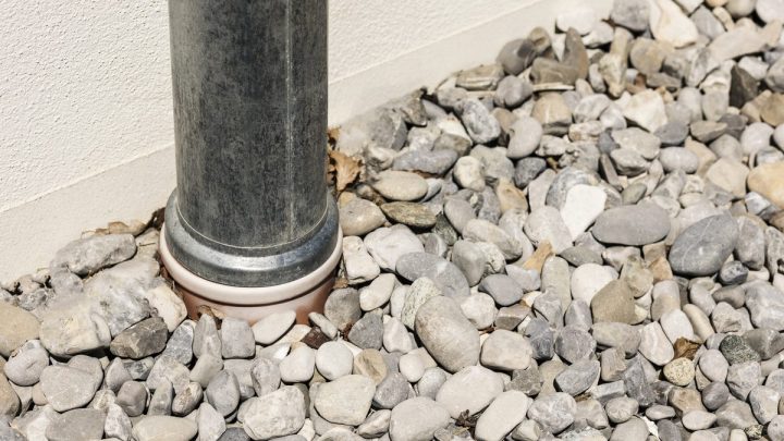 Sewer pipe surrounded by drainage gravel and stone beside a building