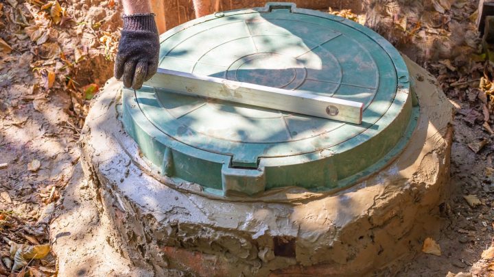 Worker levelling the access hatch on a concrete ring septic tank