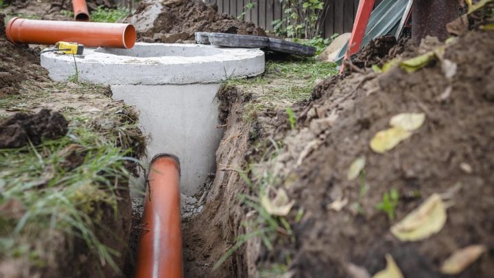 Underground septic tank built from concrete rings, open trench around it
