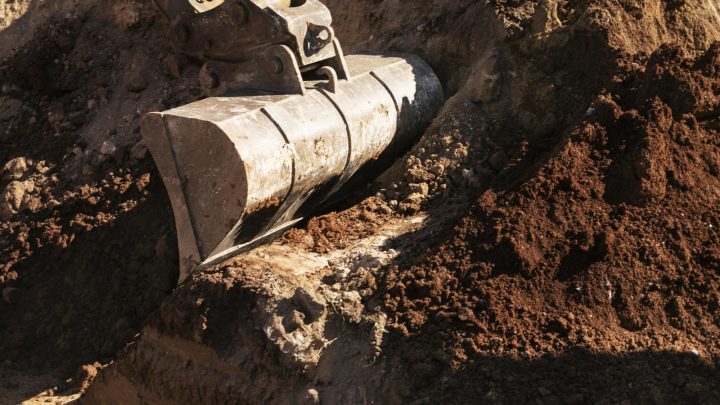 Excavator bucket digging soil, open ground