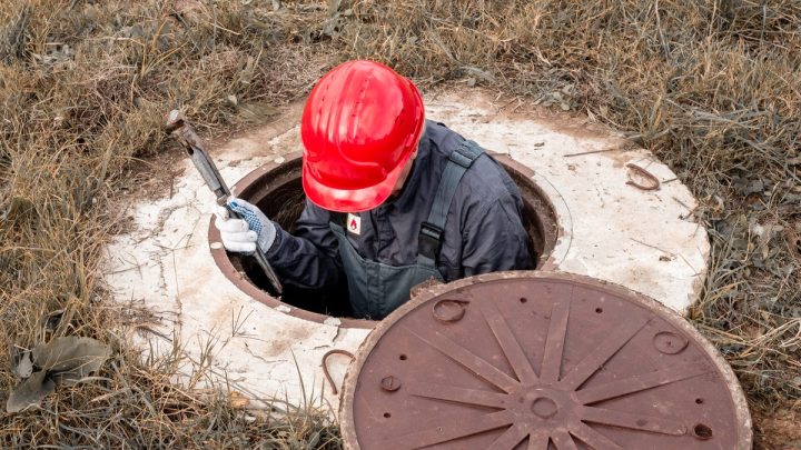 Worker inside a concrete chamber tightening fittings with a wrench