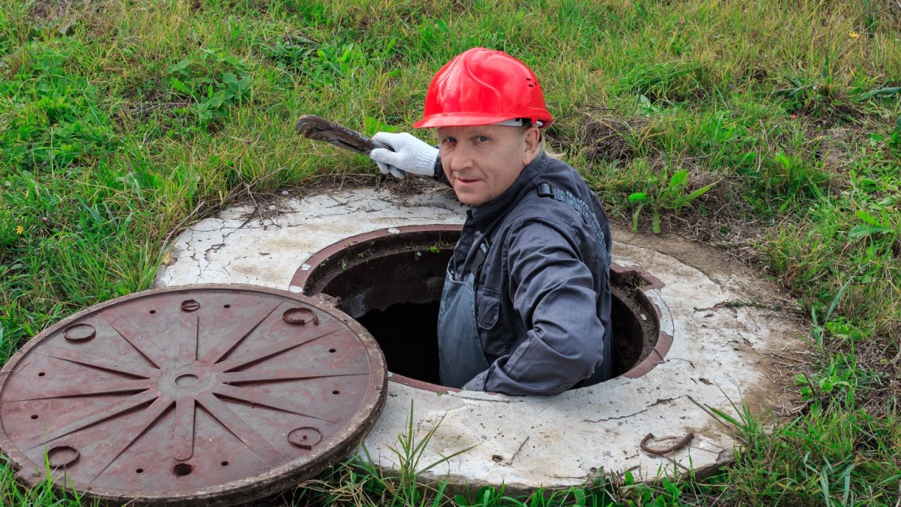 Technician down inside an open concrete chamber doing repairs