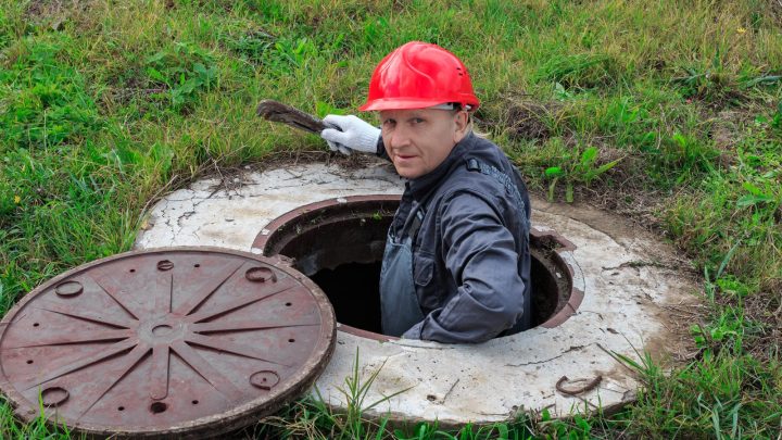 Technician down inside an open concrete chamber doing repairs