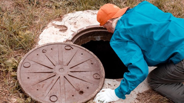 Worker checking a meter inside an underground chamber, rural setting