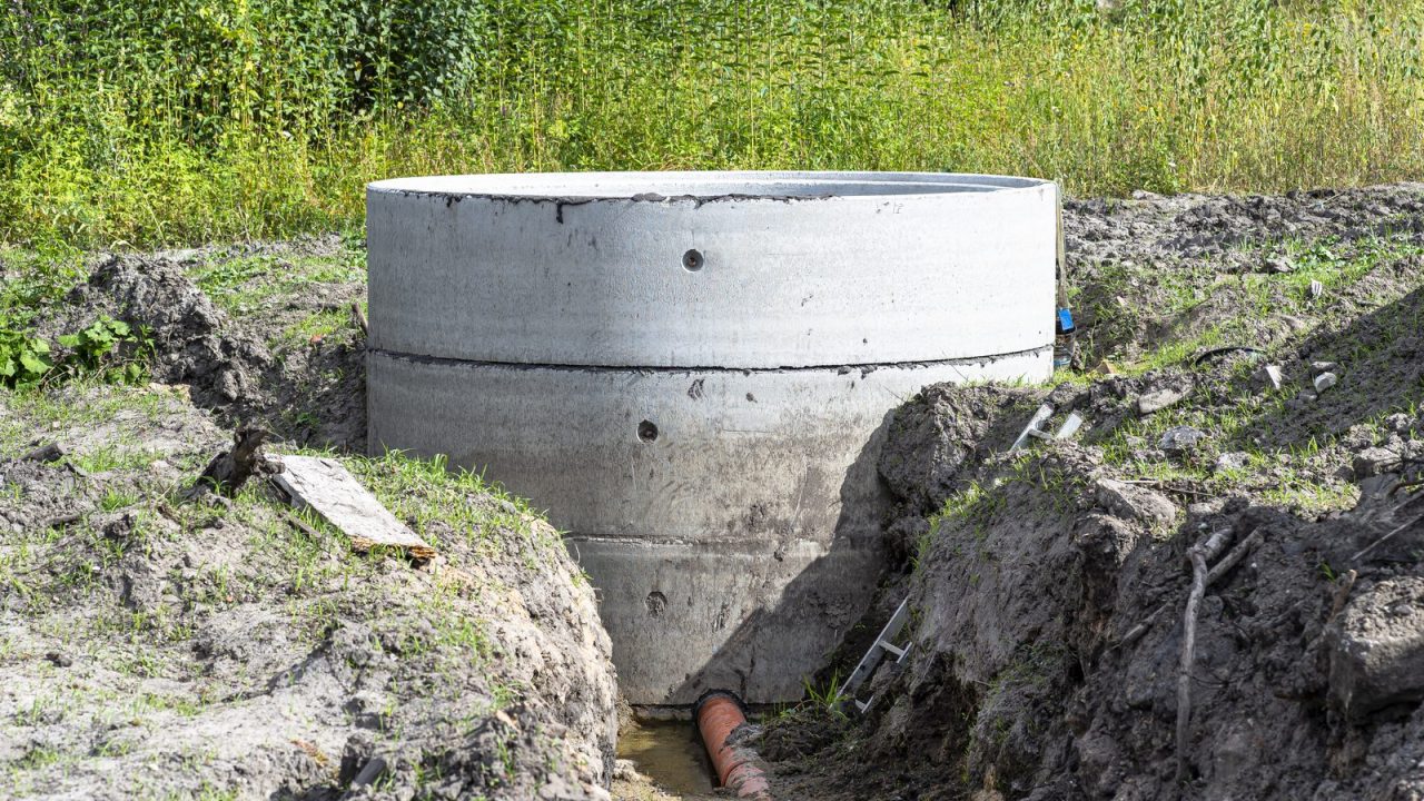 Interior of concrete ring septic tank with orange inlet drainpipe visible