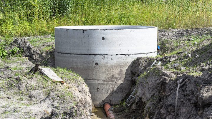 Interior of concrete ring septic tank with orange inlet drainpipe visible