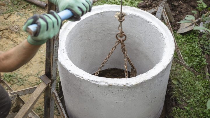 Concrete ring being lowered into the ground for a septic or sewer well