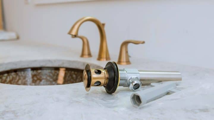 Worker assembling and installing a bathroom sink and its waste pipe