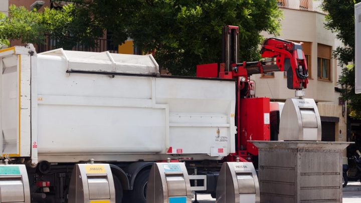 Service truck lifting a bin on a residential street