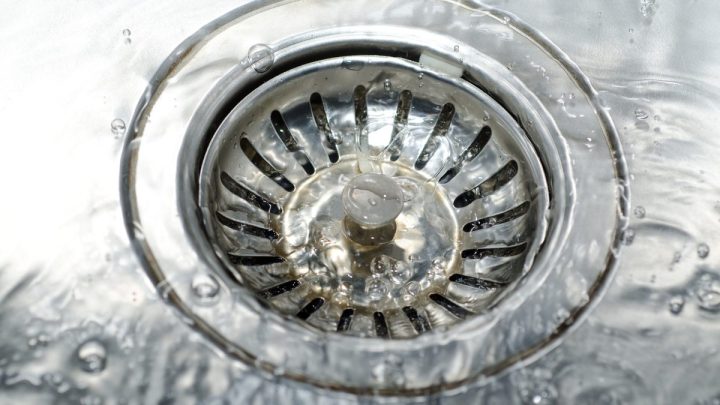 Water running into a floor/shower drain grate, seen from above